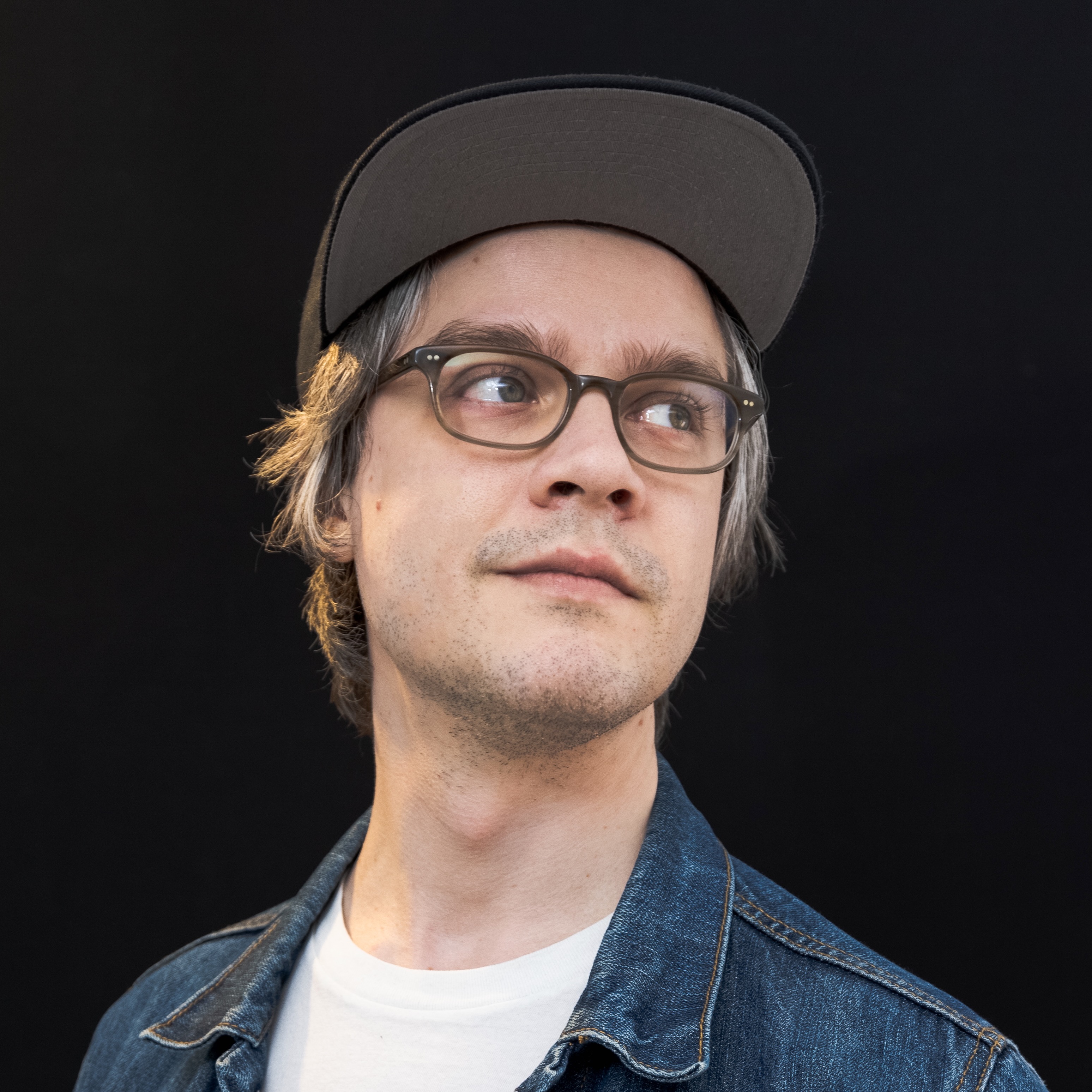 Portrait image of Jason Hawkins, wearing a blue denim jacket, on a dark background, and facing up and to the right.